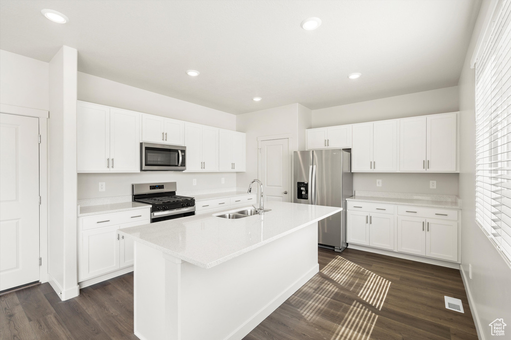Kitchen featuring stainless steel appliances, dark wood-style flooring, a kitchen island with sink, white cabinets, and recessed lighting