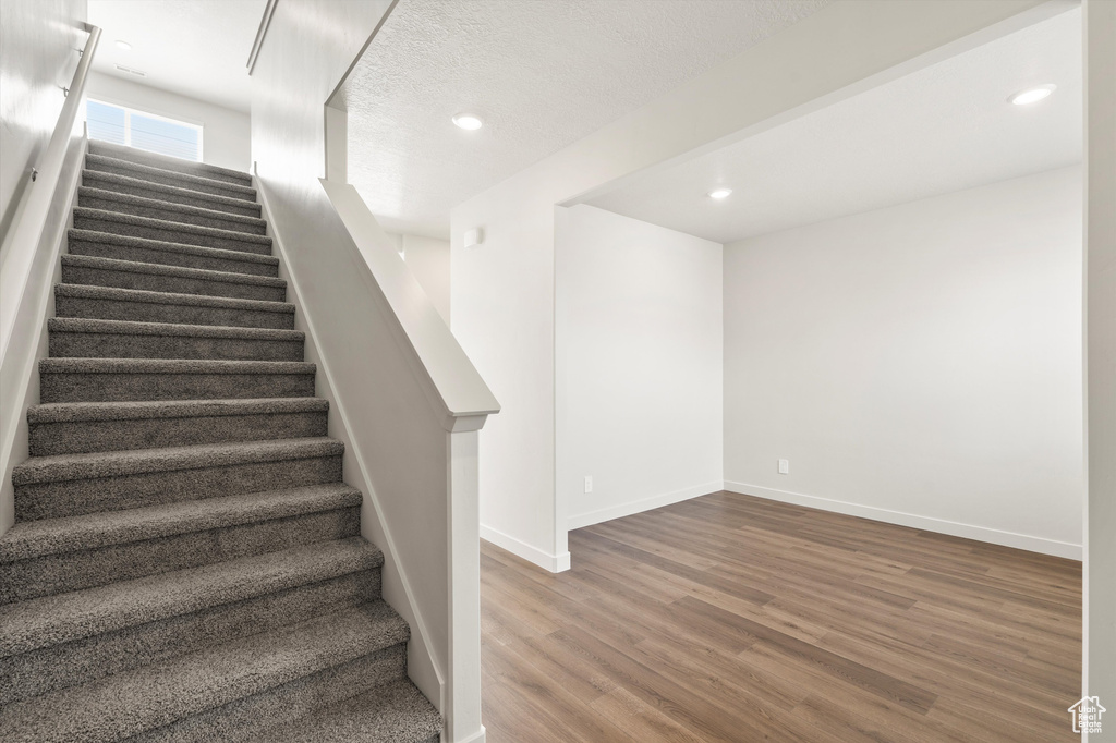 Stairway with wood finished floors and recessed lighting