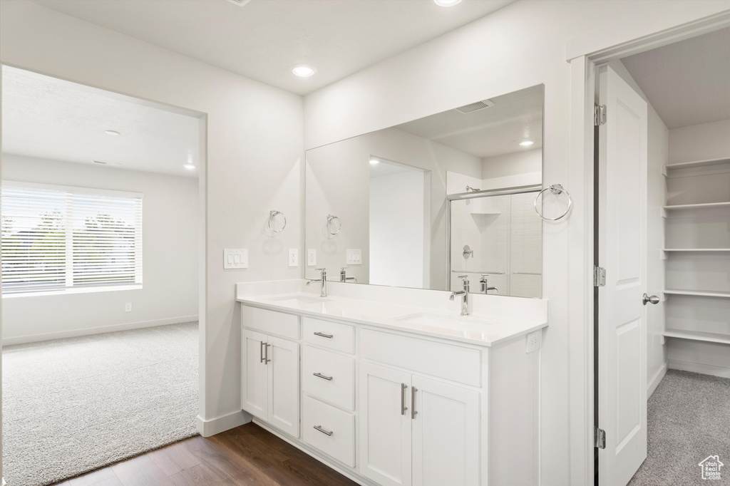 Full bathroom featuring a shower stall, double vanity, recessed lighting, and wood finished floors