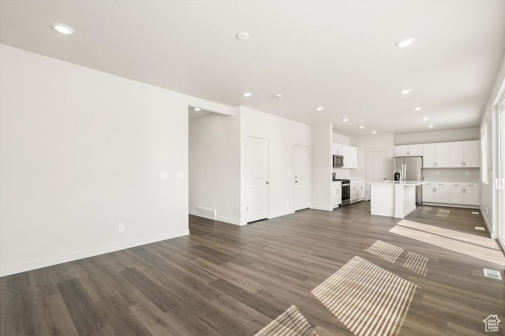 Unfurnished living room with recessed lighting and dark wood-style flooring
