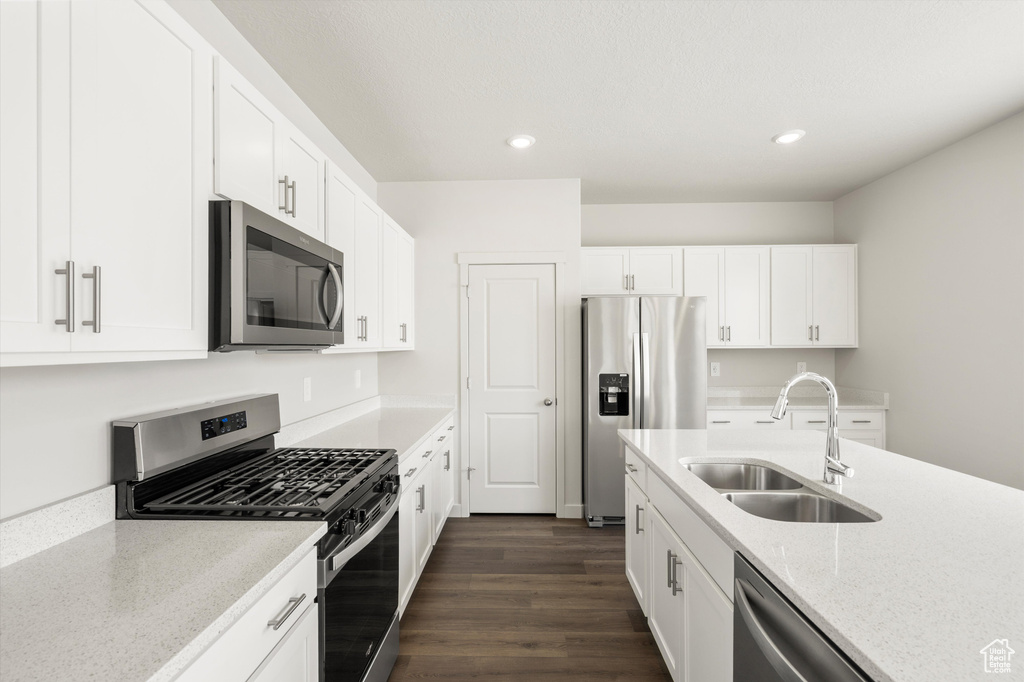 Kitchen with appliances with stainless steel finishes, recessed lighting, white cabinets, dark wood-style floors, and light stone countertops