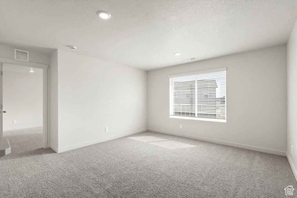 Empty room featuring light colored carpet, a textured ceiling, and recessed lighting
