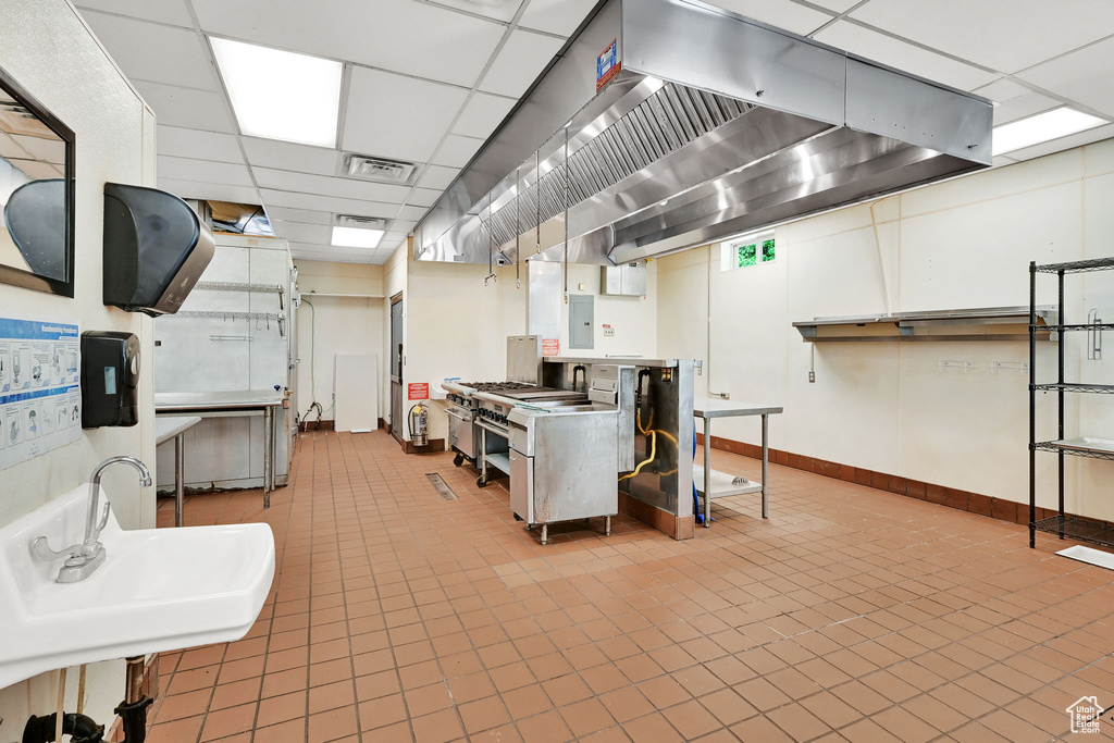 Basement featuring a paneled ceiling, light tile patterned floors, a sink, and baseboards