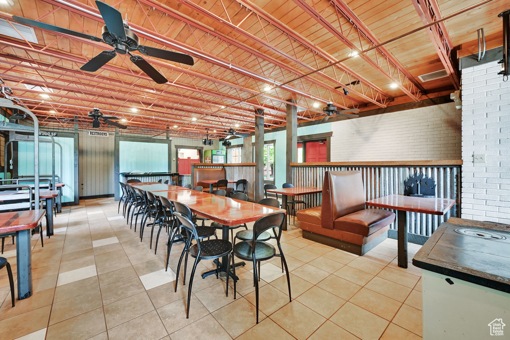 Dining room with ceiling fan, brick wall, tile patterned floors, and wood ceiling