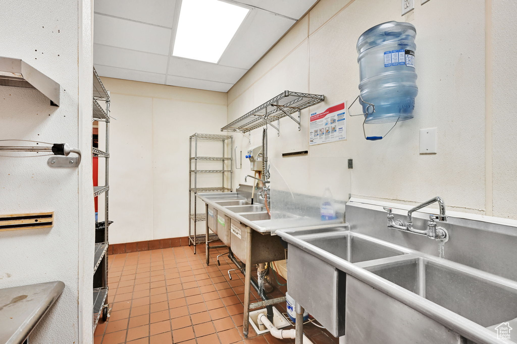 Kitchen with a sink, light tile patterned flooring, and a paneled ceiling