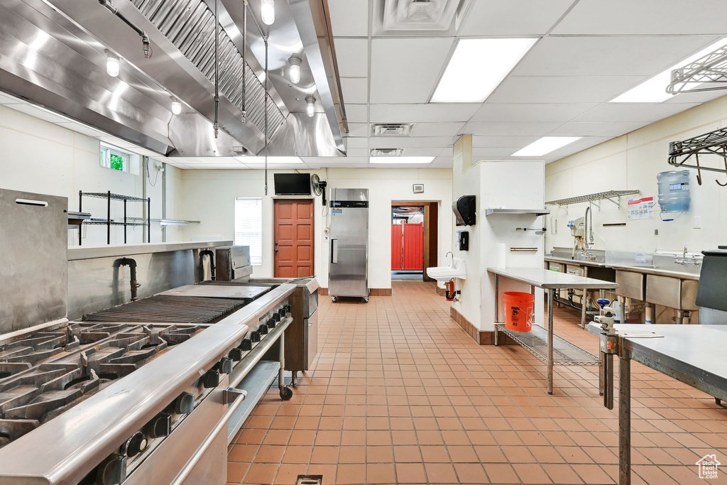 Kitchen with stainless steel fridge, tile patterned floors, and a drop ceiling