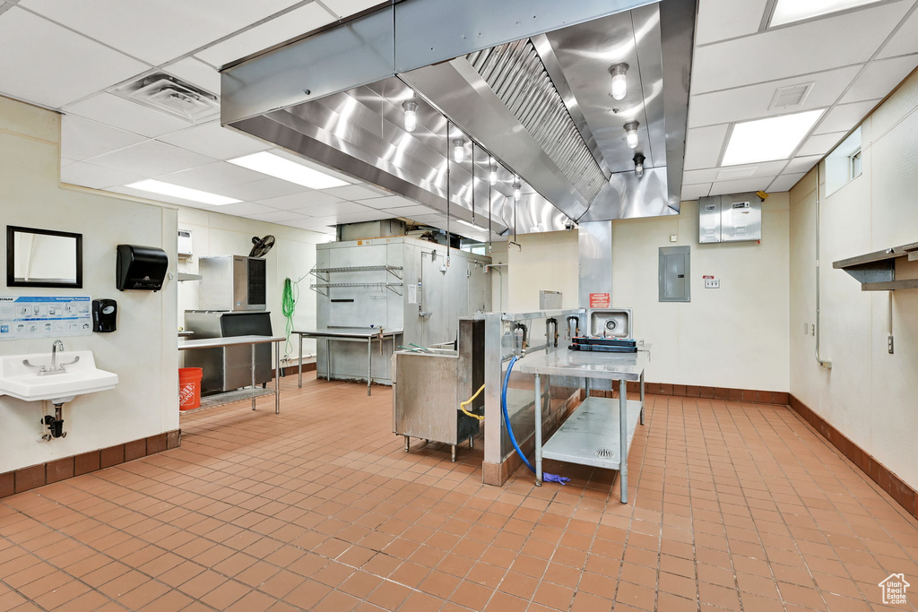 Kitchen with baseboards, a sink, a paneled ceiling, tile patterned flooring, and electric panel