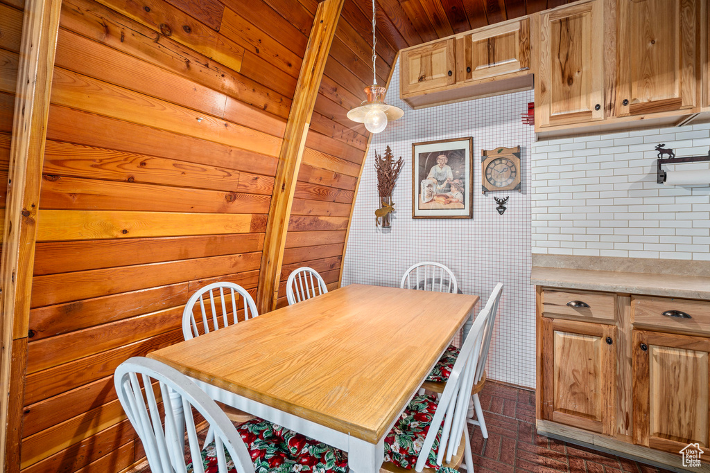 Dining space with brick patterned floors, wooden ceiling, wooden walls, and wallpapered walls