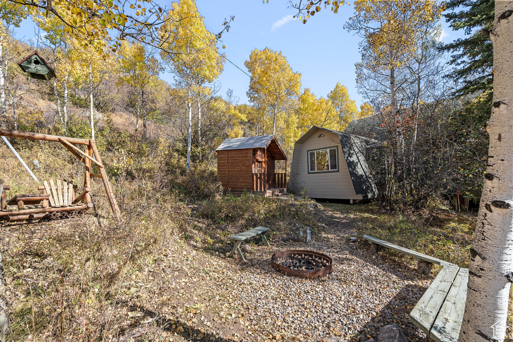 View of yard with a fire pit, an outbuilding, and a shed