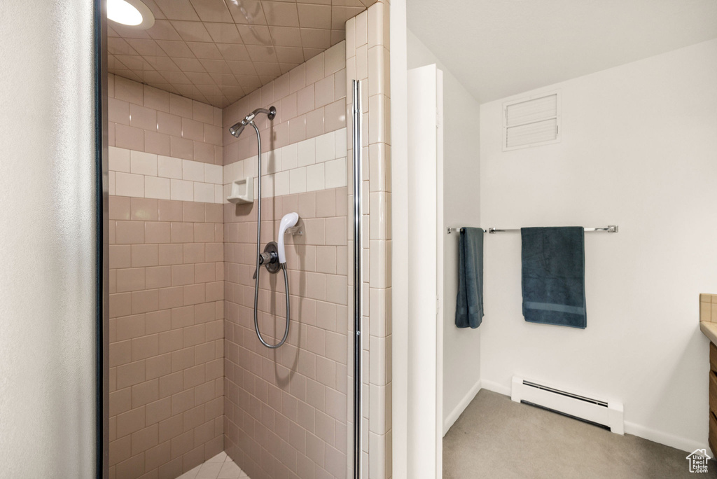 Bathroom with baseboard heating, a tile shower, and baseboards