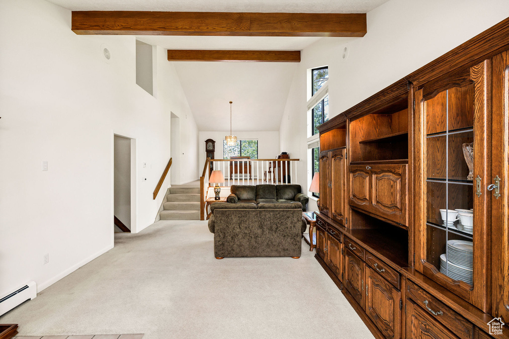 Living area with a baseboard radiator, high vaulted ceiling, light carpet, stairs, and beamed ceiling