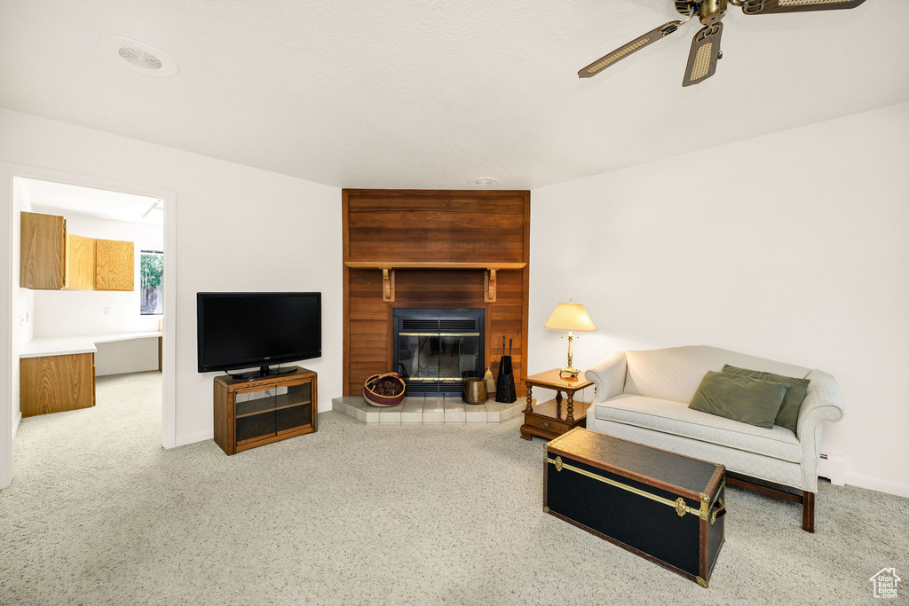 Living room featuring ceiling fan, a tile fireplace, and baseboards