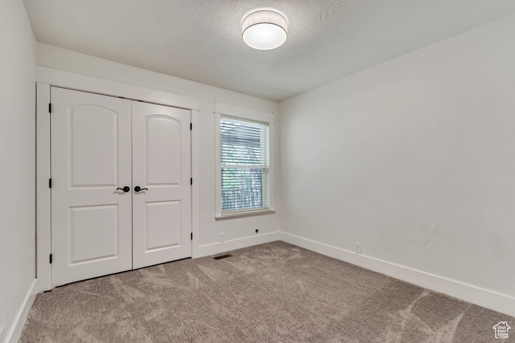 Unfurnished bedroom featuring carpet, baseboards, a closet, and a textured ceiling