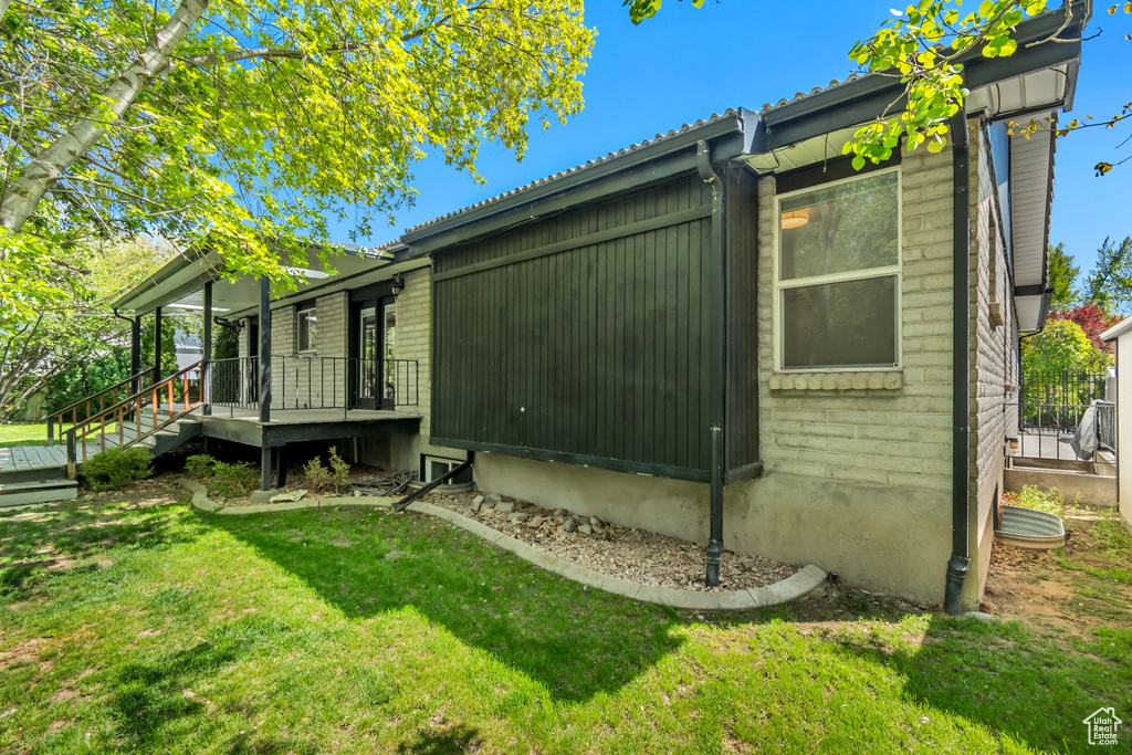 View of side of home featuring a lawn and covered porch