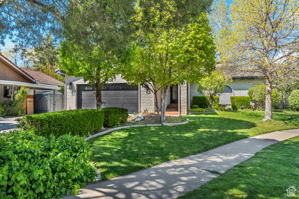 Obstructed view of property featuring brick siding, an attached garage, and a gate