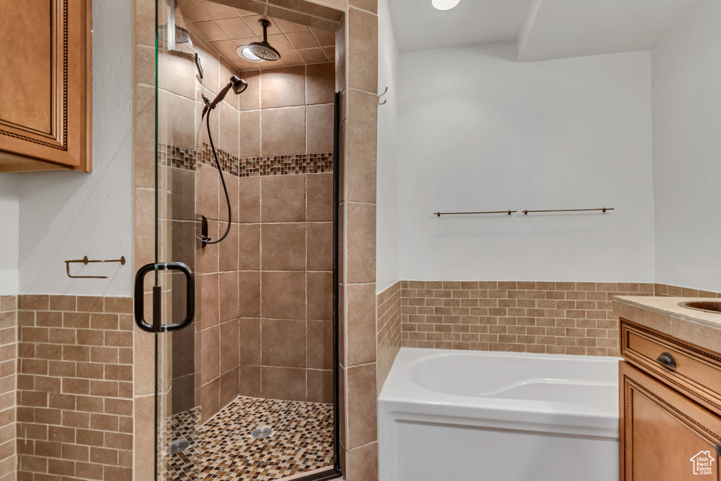 Full bathroom featuring a stall shower, a garden tub, and vanity