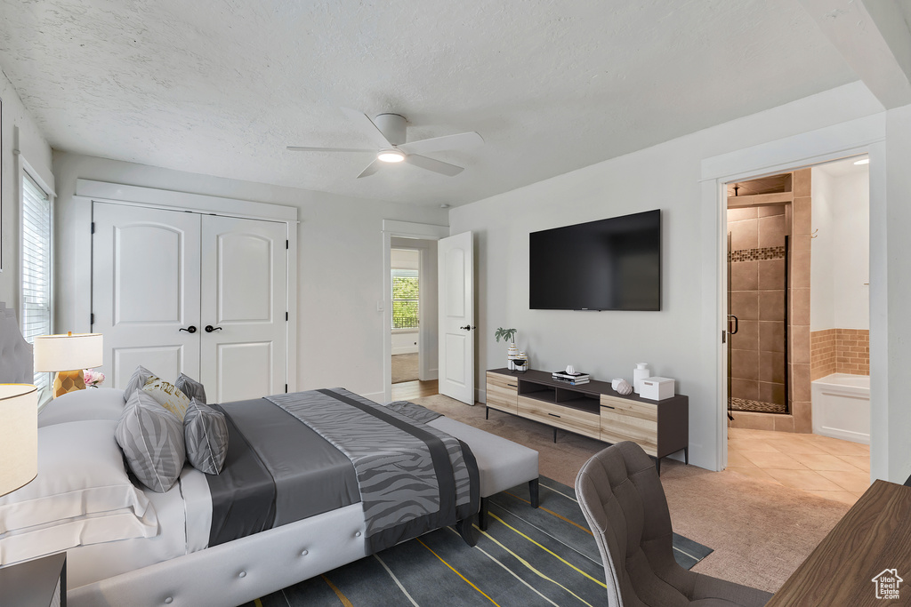 Bedroom with a closet, connected bathroom, ceiling fan, carpet floors, and tile patterned floors