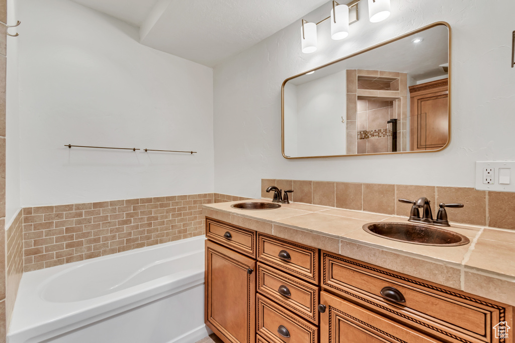 Full bathroom featuring a garden tub, a shower stall, and double vanity