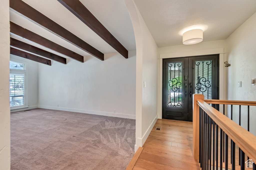 Foyer entrance with beam ceiling, baseboards, and french doors