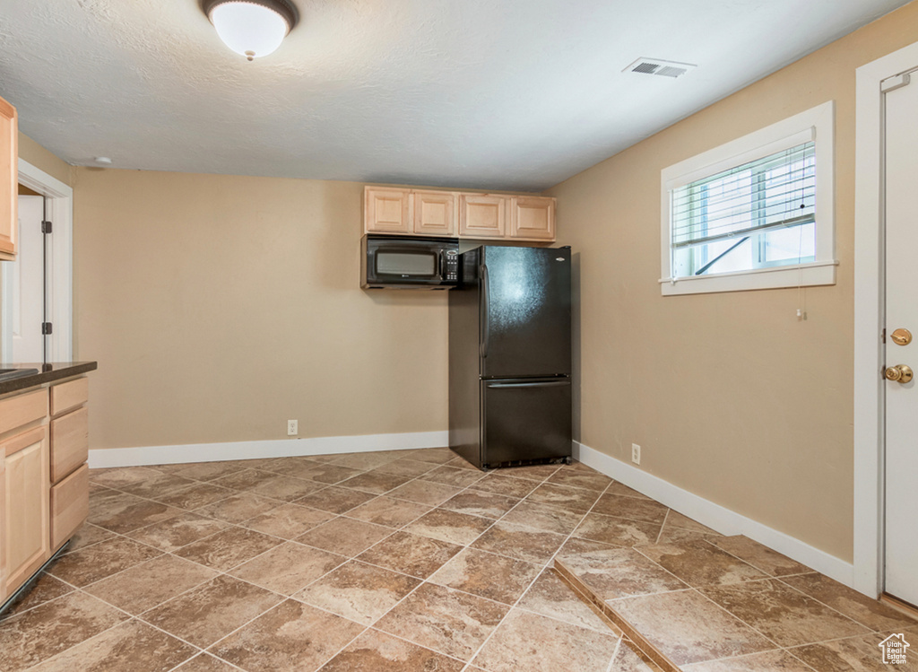 Kitchen featuring black appliances, light brown cabinets, baseboards, and light stone finish flooring