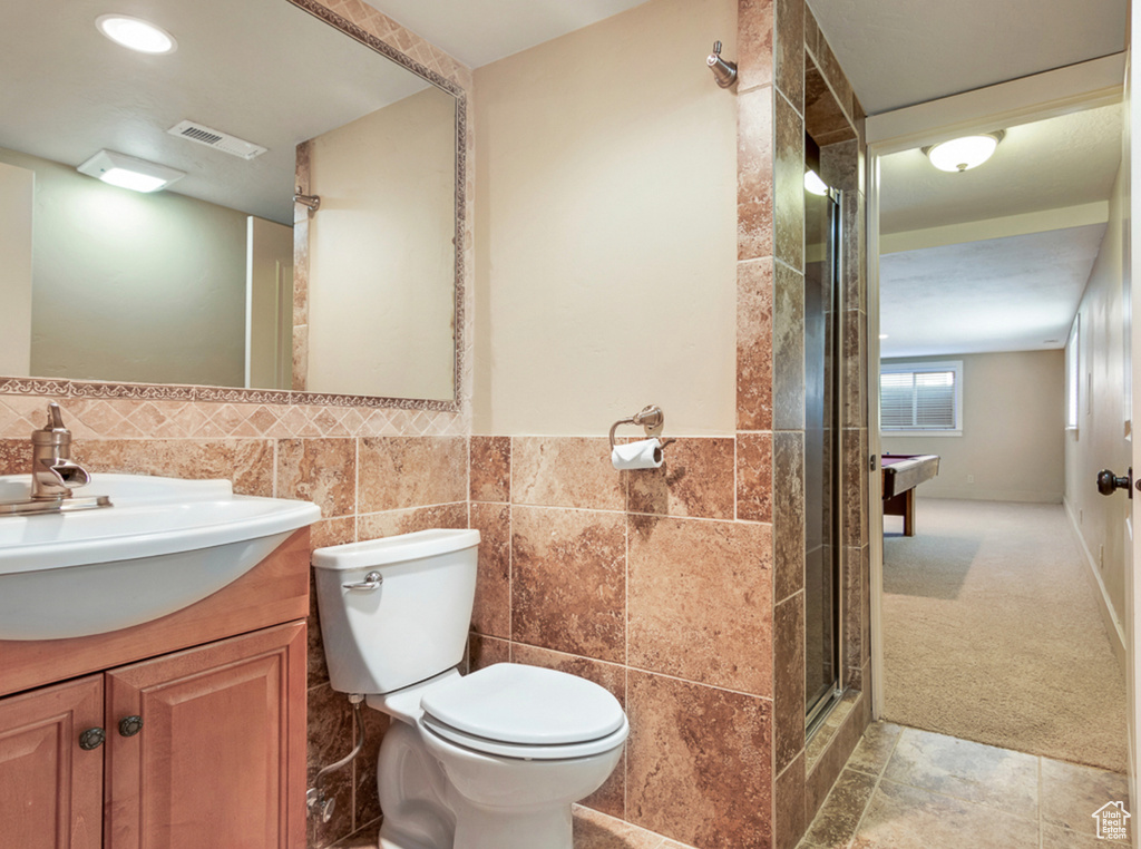 Bathroom featuring tile walls, toilet, a shower stall, and vanity