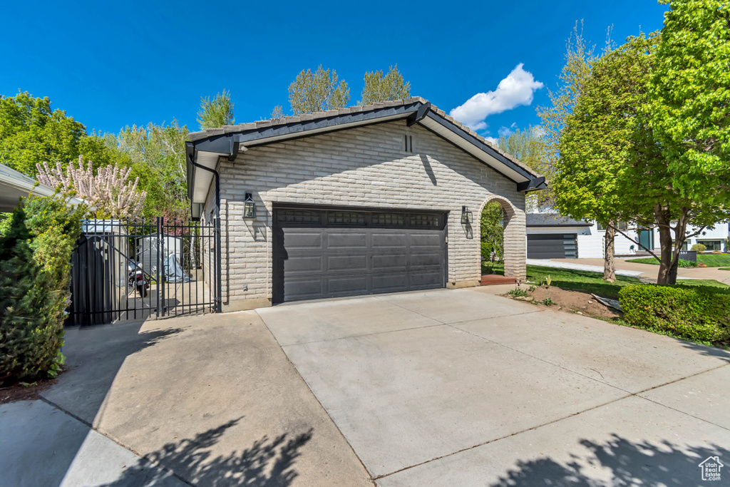 View of home\'s exterior featuring fence, brick siding, an attached garage, and concrete driveway