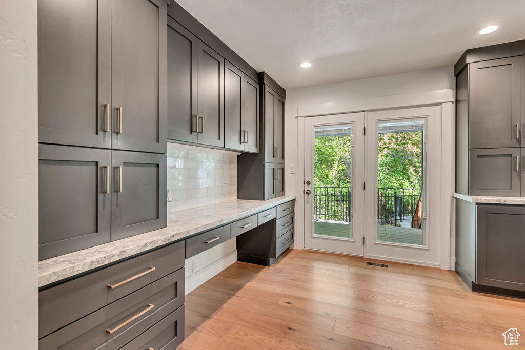 Unfurnished office with built in desk, light wood finished floors, and recessed lighting