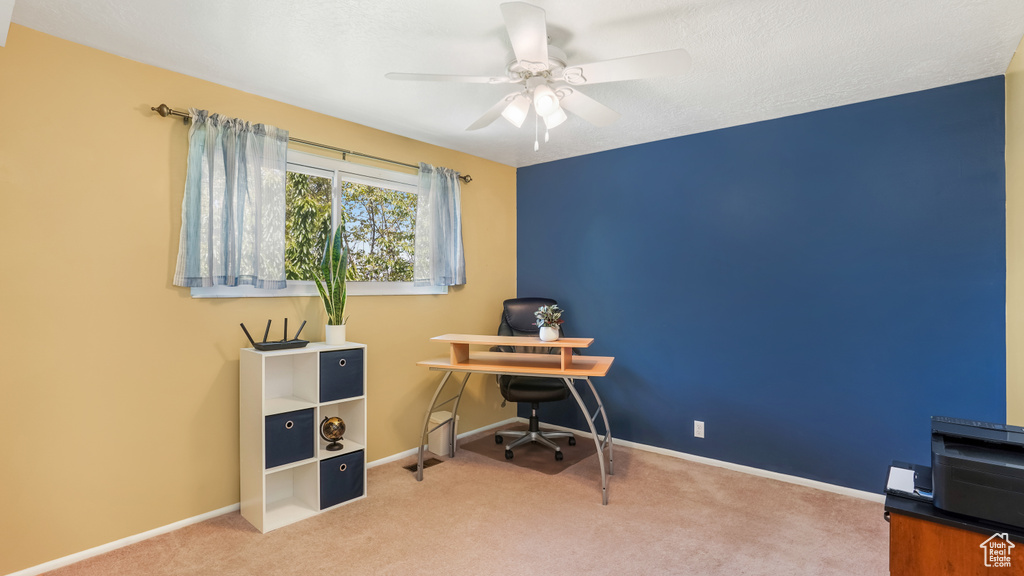 Carpeted home office with ceiling fan and baseboards