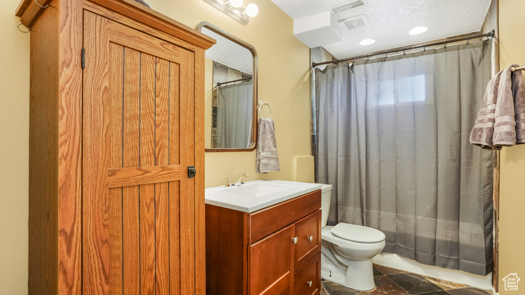 Bathroom featuring toilet, vanity, a shower with shower curtain, and a textured ceiling