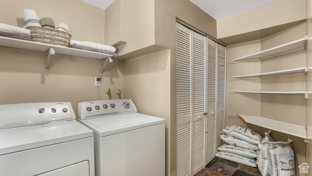 Laundry area featuring independent washer and dryer and dark stone finish flooring