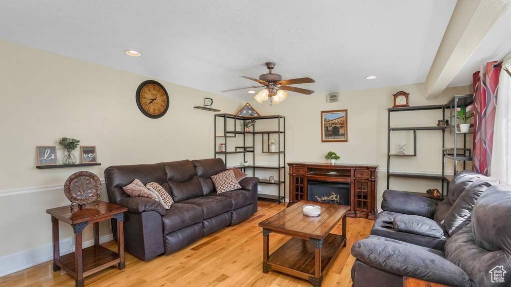 Living area with a ceiling fan, light wood finished floors, baseboards, and recessed lighting