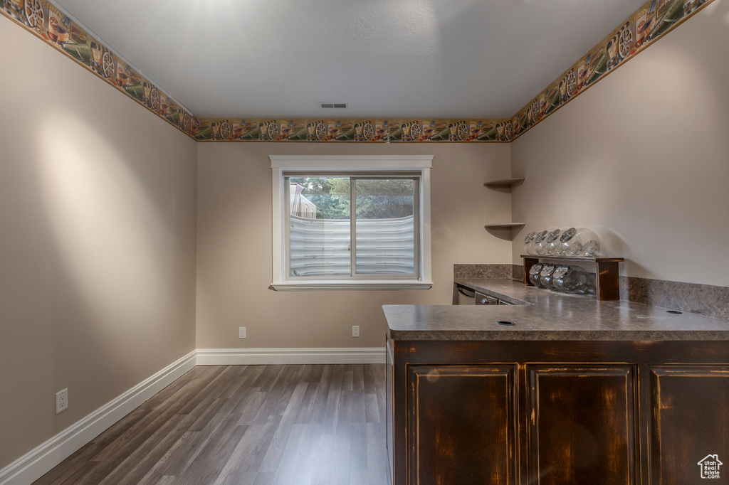 Kitchen with dark wood-style flooring, dark brown cabinets, baseboards, dark countertops, and a peninsula