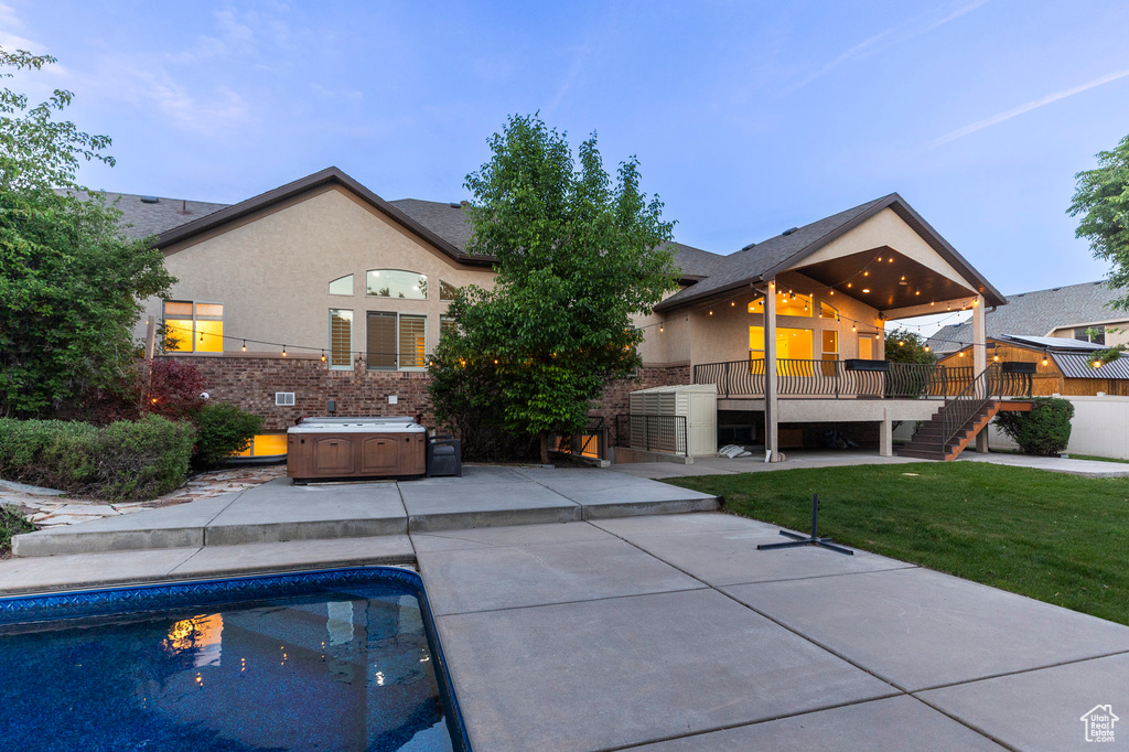 Rear view of property featuring a patio area, stairs, a hot tub, a wooden deck, and a yard