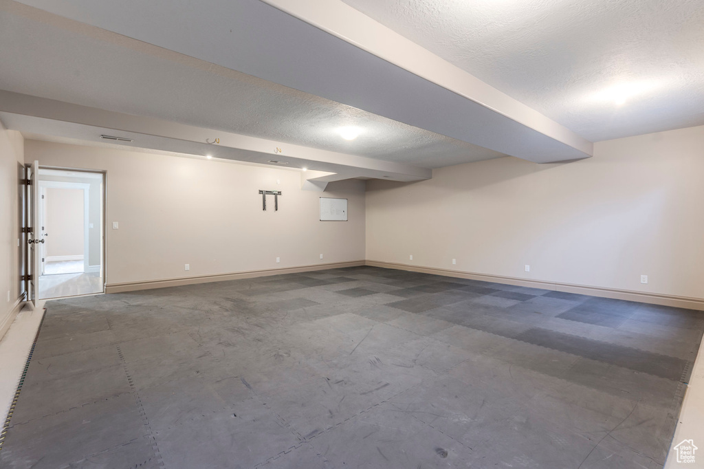 Finished below grade area with baseboards and a textured ceiling