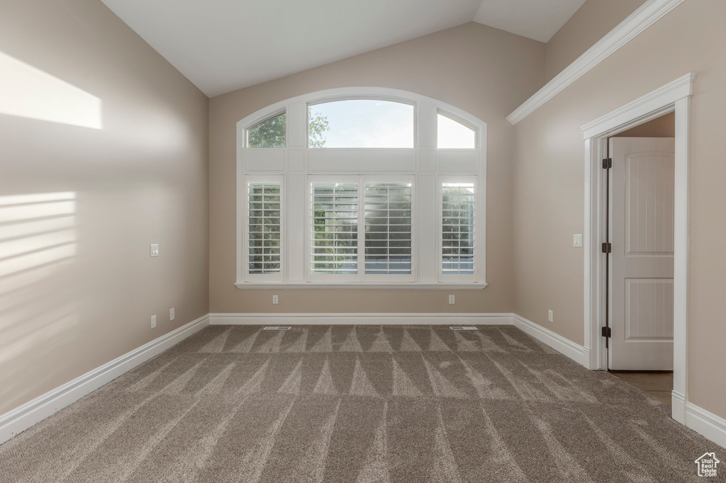 Carpeted spare room featuring lofted ceiling and baseboards