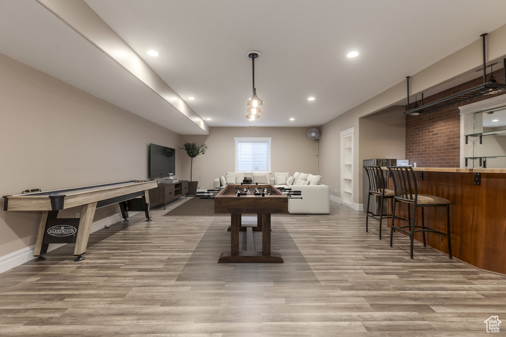 Game room featuring wood finished floors, baseboards, recessed lighting, and bar
