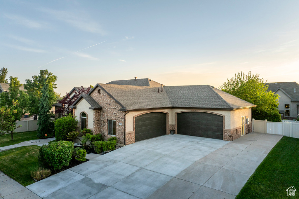 French country style house featuring driveway, a garage, stone siding, stucco siding, and roof with shingles