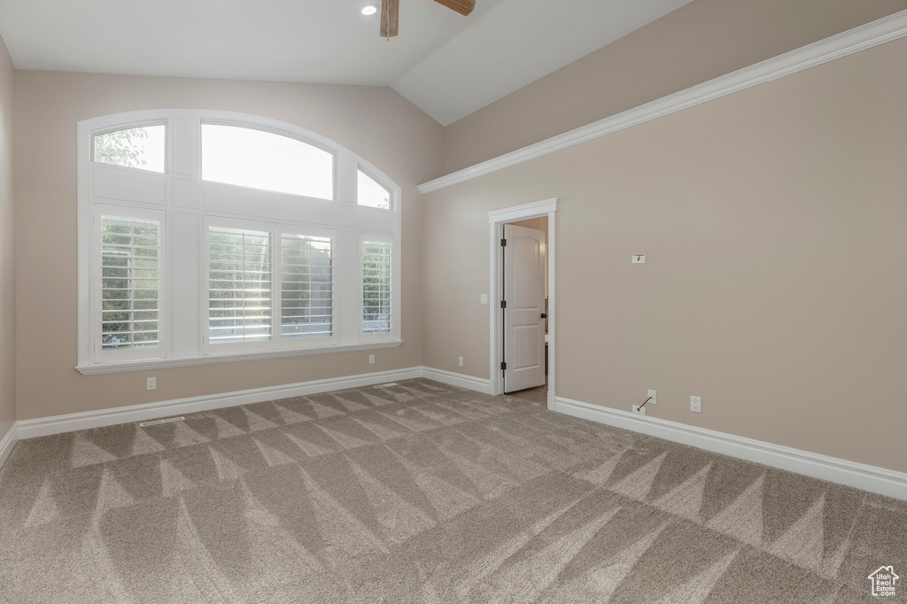 Empty room with ceiling fan, carpet flooring, baseboards, and lofted ceiling