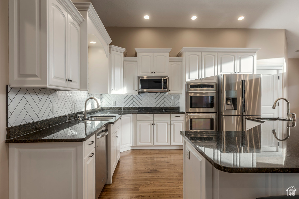 Kitchen with appliances with stainless steel finishes, a sink, white cabinetry, and recessed lighting