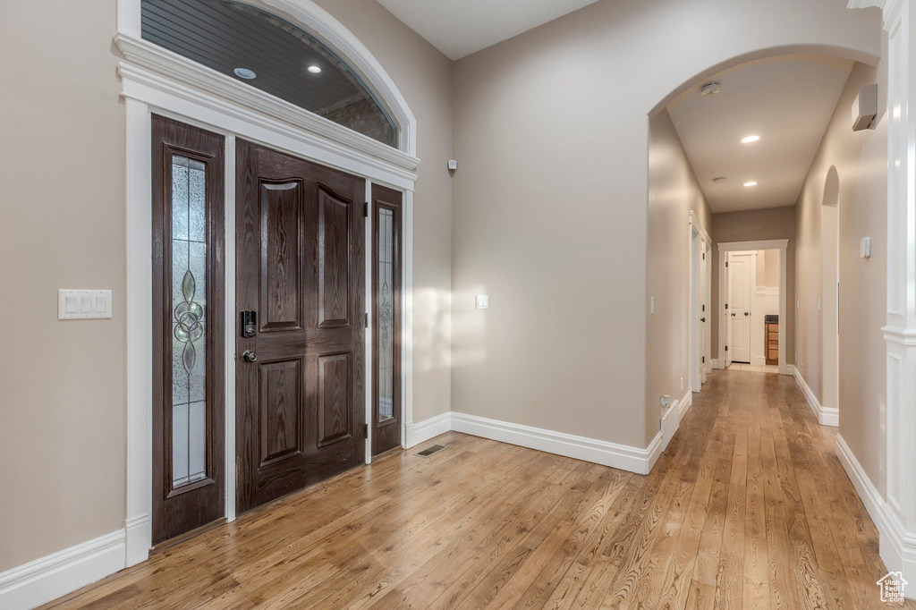 Foyer featuring arched walkways, light wood-type flooring, baseboards, and recessed lighting