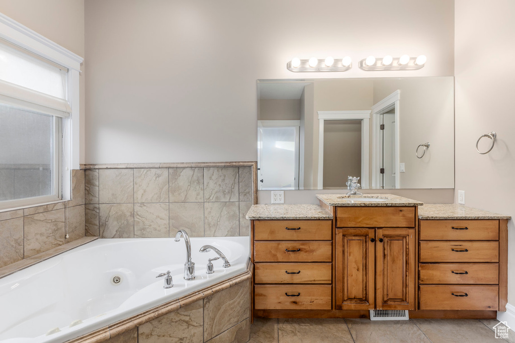 Bathroom featuring a tub with jets and vanity