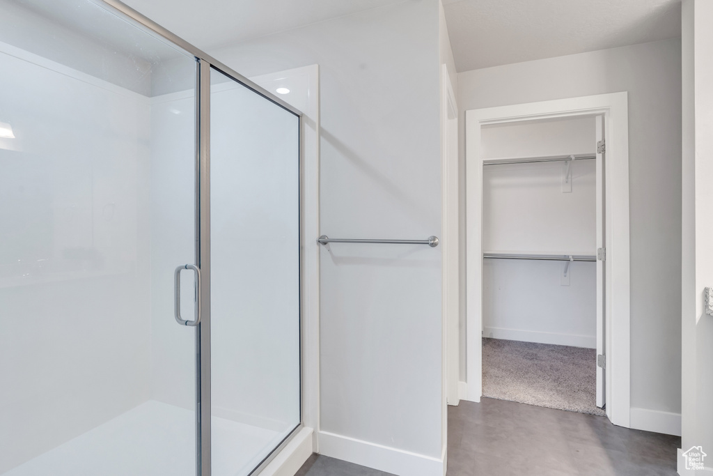 Full bathroom featuring a stall shower, a spacious closet, and baseboards