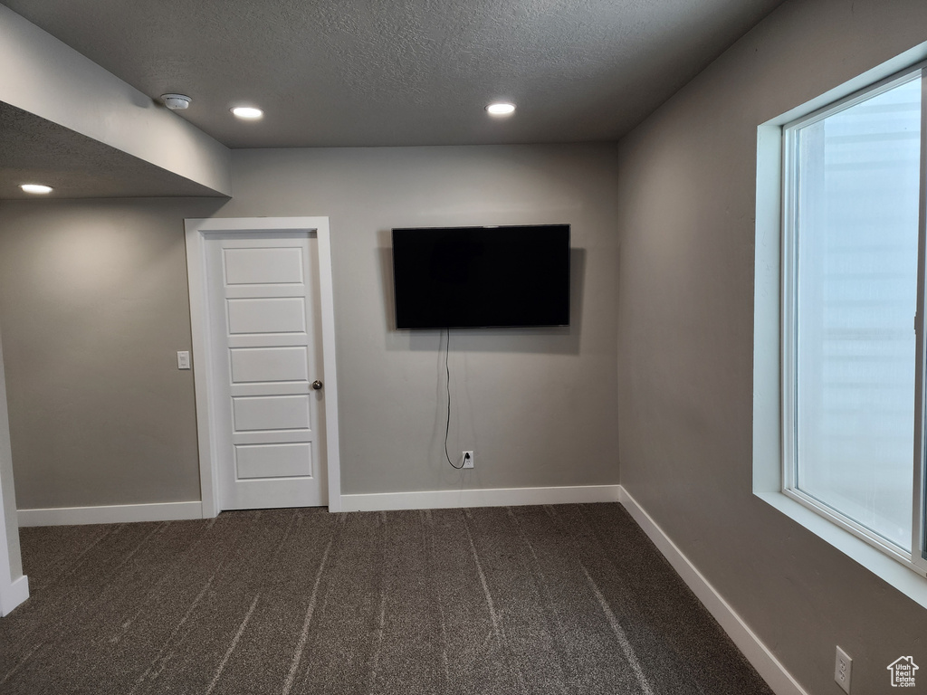 Basement with baseboards, dark carpet, a textured ceiling, recessed lighting, and plenty of natural light