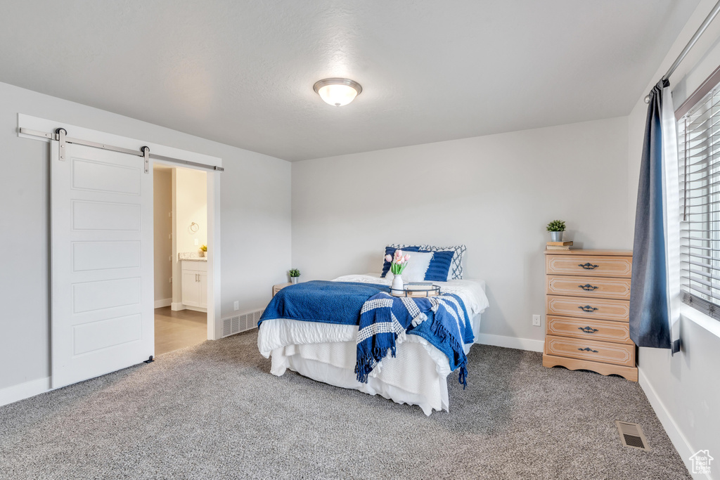 Bedroom featuring a barn door, carpet flooring, baseboards, and connected bathroom