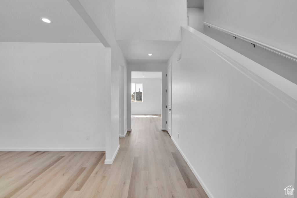Hallway featuring light wood-style floors, baseboards, and recessed lighting