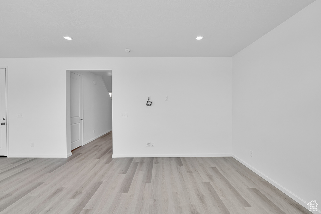 Unfurnished room with light wood finished floors, baseboards, and recessed lighting