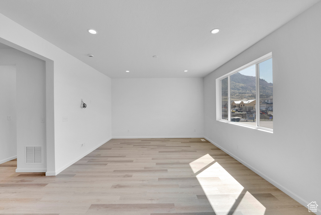 Unfurnished room with recessed lighting, a mountain view, light wood finished floors, and baseboards