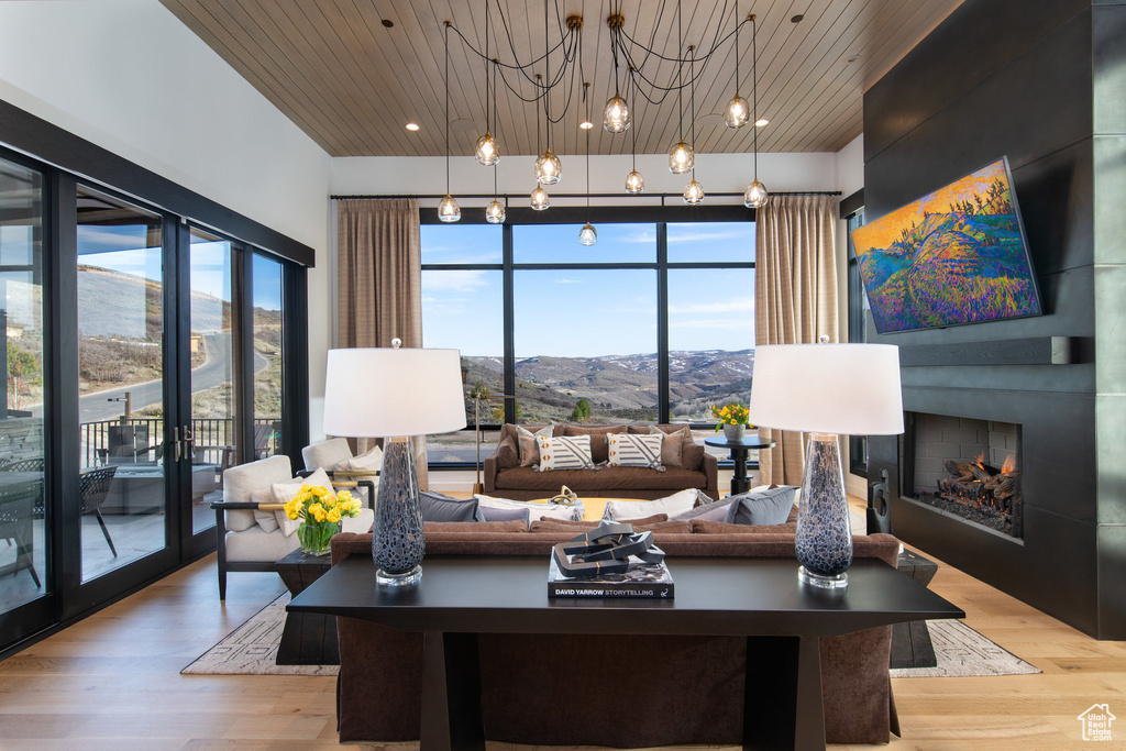 Living room featuring a lit fireplace, wooden ceiling, light wood-style floors, and a chandelier