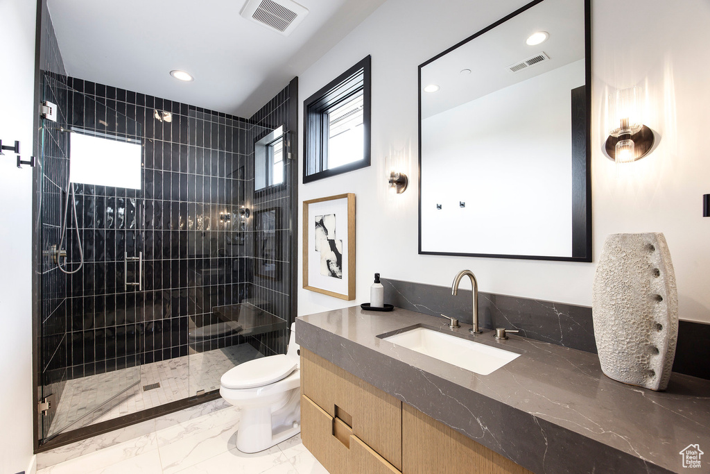 Bathroom with marble finish flooring, a tile shower, toilet, recessed lighting, and vanity