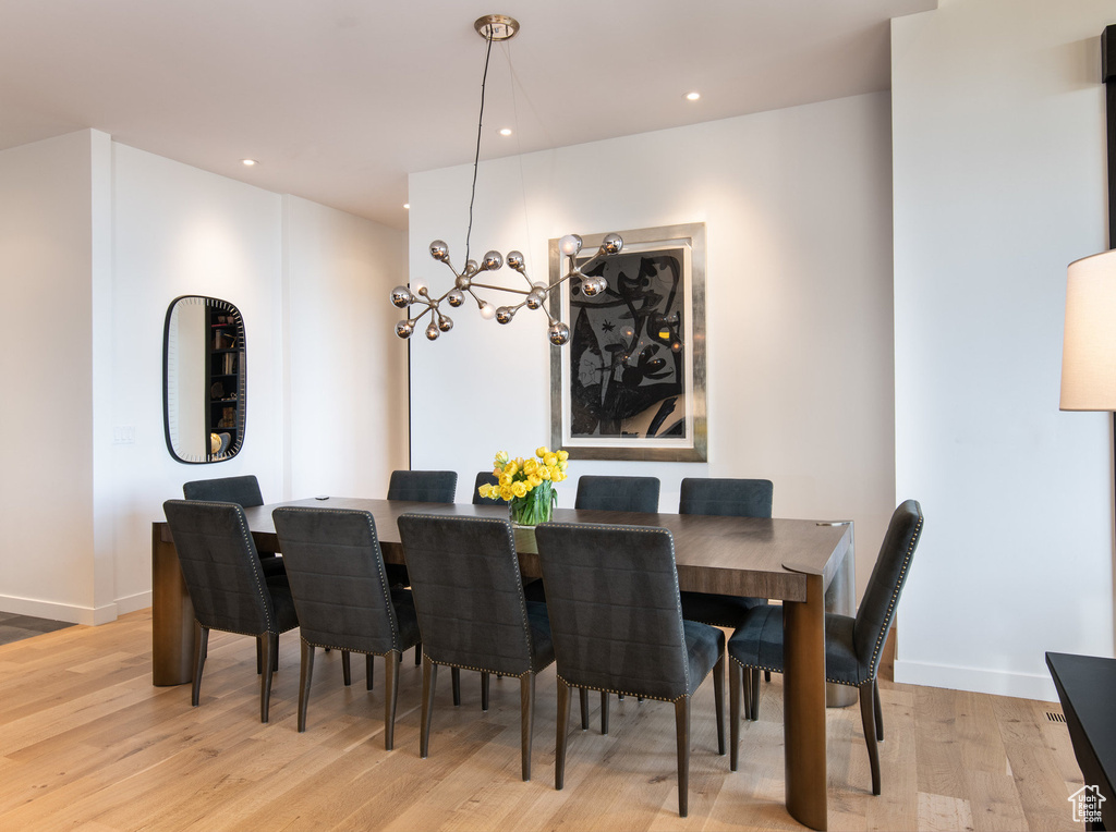 Dining area featuring light wood-style floors, a chandelier, baseboards, and recessed lighting